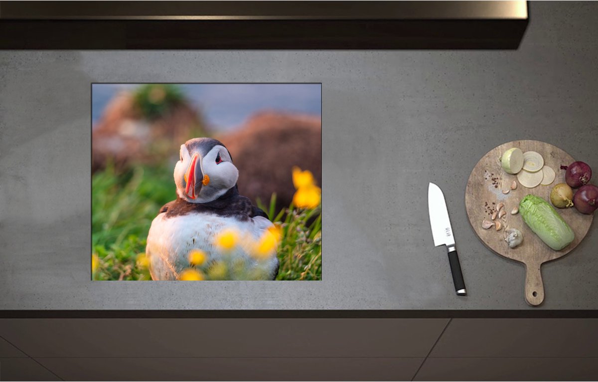 Inductieplaat Beschermer - Aankijkende Papegaaiduiker Vogel in Landschap met Gele Bloemetjes - 58x50 cm - 2 mm Dik - Inductie Beschermer - Bescherming Inductiekookplaat - Kookplaat Beschermer van Zwart Vinyl