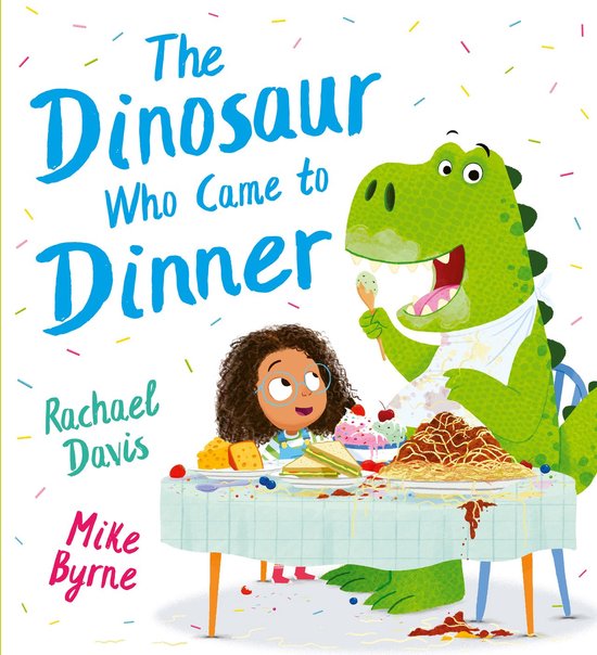 Een groene dinosaurus eet spaghetti aan een tafel vol met eten. Een meisje kijkt toe.