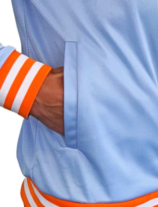 Detail van de zak van een lichtblauwe trainingsjas met oranje en witte gestreepte boorden.