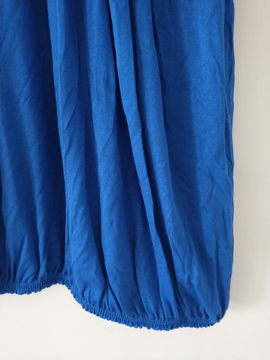 Gedetailleerde close-up van de gerimpelde zoom van een koningblauwe top.