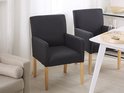 Deux chaises de salle à manger noires à une table blanche, avec une partie d'un canapé beige.