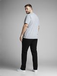 Man in een grijze T-shirt en zwarte jeans, staat met de rug naar de camera.
