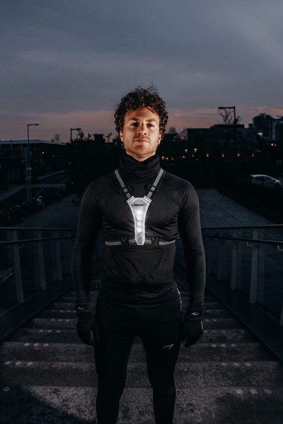 Man met krullend haar draagt een zwart shirt en draagt een wit Avento veiligheidsvest met LED-verlichting.