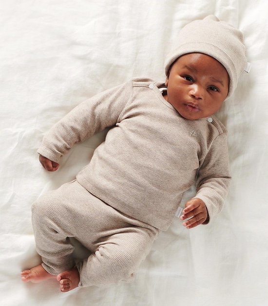 Baby in een taupe geribbelde longsleeve en broek van Noppies, met bijpassende muts.