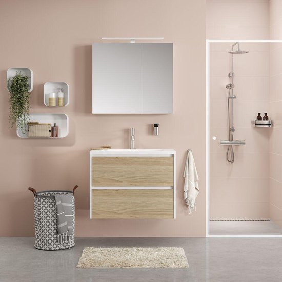 Badkamer met roze tegels, witte wandkast, houten lades en een douchecabine.