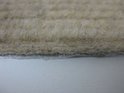 Zij-aanzicht van de beige stof van een trapmat met zachte vezels en antislip onderkant.