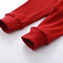 De geribbelde broekspijpen van de rode broek met elastische boorden.
