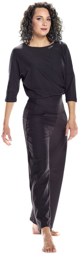 Model draagt een zwarte, wijde driekwartmouw top en bijpassende zwarte broek met hoge taille en steekzakken.