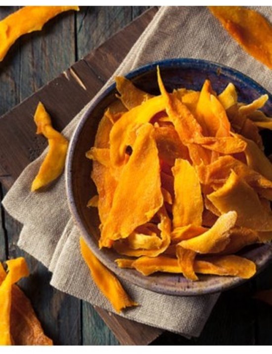Een kom gevuld met gedroogde mangostukjes op een rustieke houten tafel.