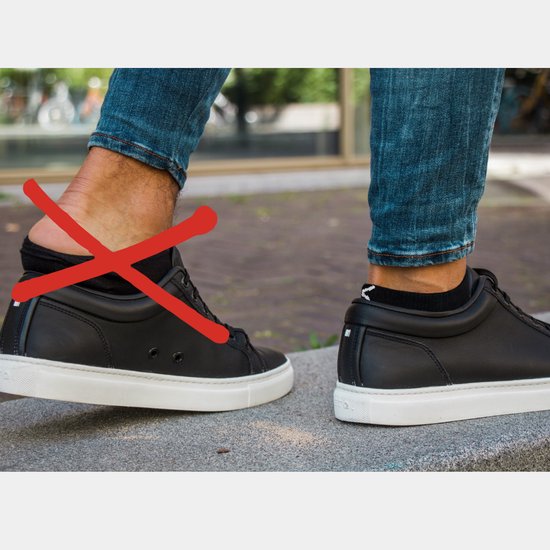 Drie paar zwarte lage sneakersokken. Een rode kruis over de linkersok op de linker voet die afzakt.