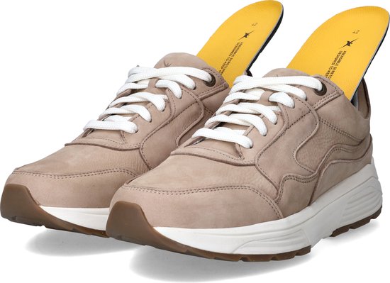 Lichtbruine leren sneakers met witte veters, witte zolen en gele inlegzolen.