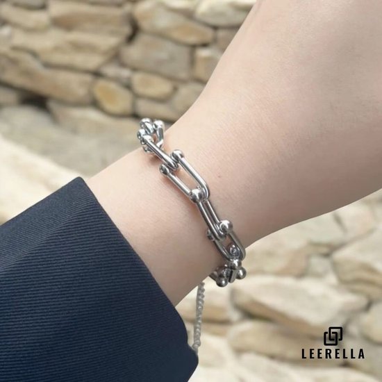 Zilverkleurige armband met U-vormige schakels, gedragen om een pols.