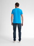 Achterkant van een man in blauw t-shirt en spijkerbroek, staand.