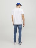 Man met blauwe pet draagt een wit T-shirt en lichtblauwe spijkerbroek.