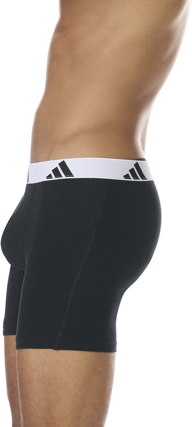 Zijkant van zwarte boxershorts met brede, witte Adidas-band met logo's.