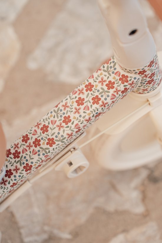 Close-up van het frame van de driewieler met een bloemenprint van rode en blauwe bloemen.