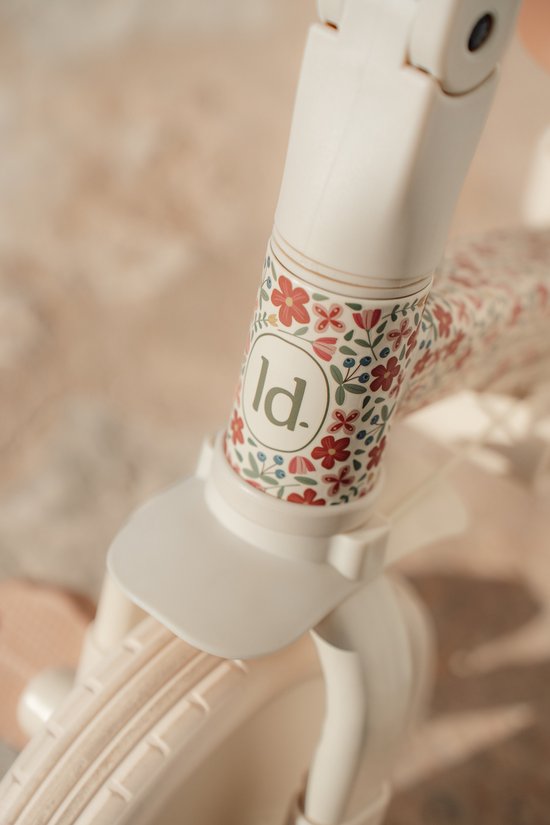 Close-up van het 'ld.' logo op een crèmekleurig frame, versierd met een bloemenprint.