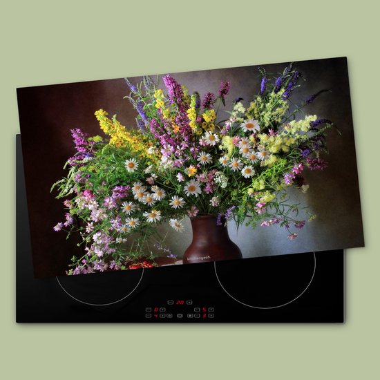 Inductiebeschermer met een stilleven boeket bloemen op een zwarte inductiekookplaat.
