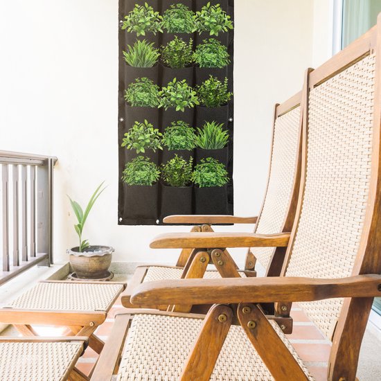 Zwarte verticale tuin met 18 vakken vol planten, hangend op een balkon bij twee ligstoelen.