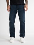 Detail van een donkerblauwe jeans, gedragen met witte sneakers.