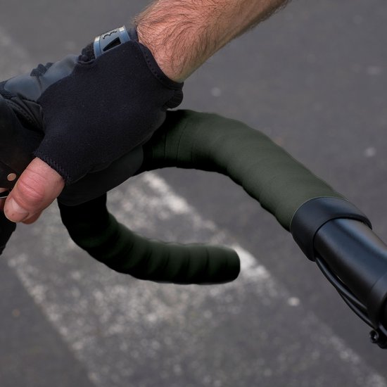 Hand in een zwart fietshandschoen omwikkelt het donkergroene stuurlint.