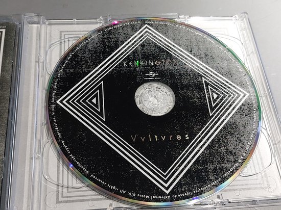 Cd van 'Vultures' met een zwart label en een geometrisch patroon, met de bandnaam 'Kensington'.