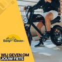 Man op zwarte fatbike met grote koplamp, rijdend op een parkeerplaats.