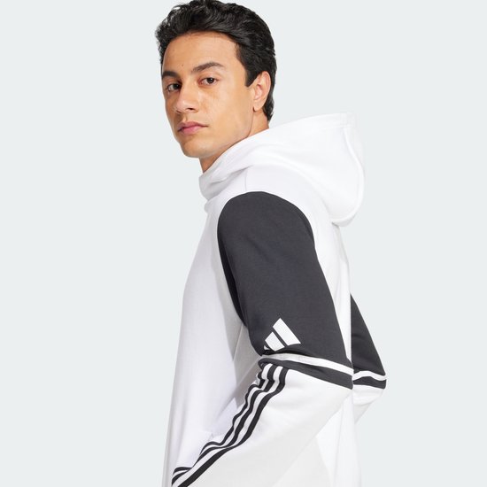 Man met een wit sweatshirt met donkergrijze mouwen en Adidas-strepen op de mouwen.