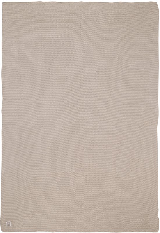 Een beige wiegdeken van gebreid katoen, plat gelegd.