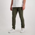 Man met groene corduroy jeans en witte sneakers, van voren gezien.