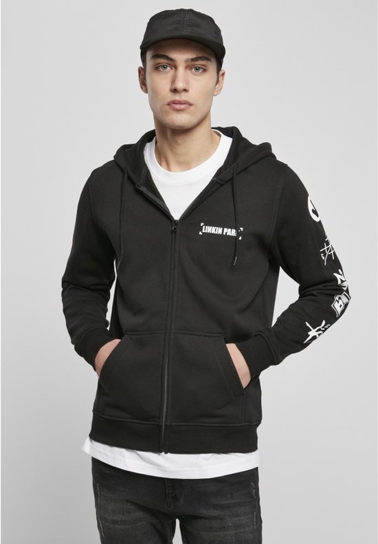 Man met pet, draagt een zwarte hoodie met ritssluiting met 'Linkin Park' logo en witte grafische prints op de mouw.