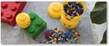 Grote rode en groene Lego-stenen, gele Lego-hoofden en bakjes gevuld met gekleurde Lego-blokjes.