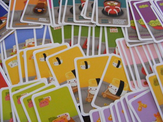 Een stapel kaarten van het spel Sushi Go Party met afbeeldingen van sushi en onigiri.