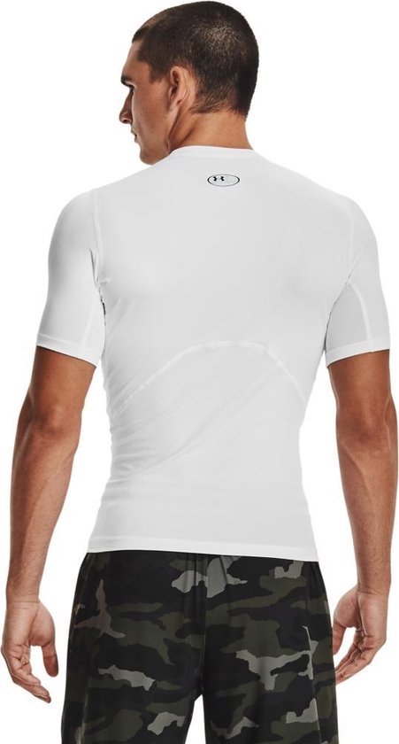 Achterkant man met wit Under Armour HeatGear sportshirt met korte mouwen en camouflage shorts.