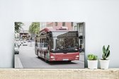 Canvas Schilderij Een vooraanzicht van een roodgekleurde bus - 30x20 cm - Wanddecoratie