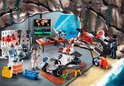 Een Playmobil avonturenscène met een witte/grijze raket, voertuigen en figuren in een grotomgeving.