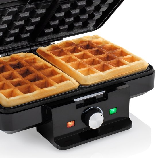 Twee goudbruine wafels in een zwart Tristar wafelijzer. Het apparaat heeft indicatielampjes en een draaiknop.