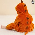 Zijaanzicht van kind in bruine dinosaurus onesie, rug naar de kijker.