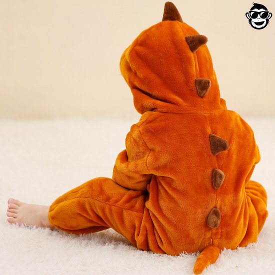 Zijaanzicht van kind in bruine dinosaurus onesie, rug naar de kijker.