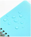 Close-up van een lichtblauwe, waterbestendige PP-materiaal omslag van een notitieboekje met waterdruppels erop.