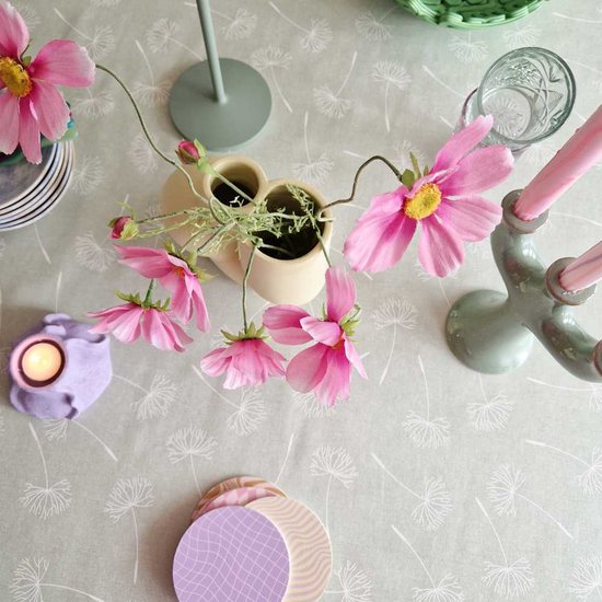 Lichtgroen tafelzeil met wit paardenbloemmotief, versierd met roze bloemen, kandelaars en een vaasje.