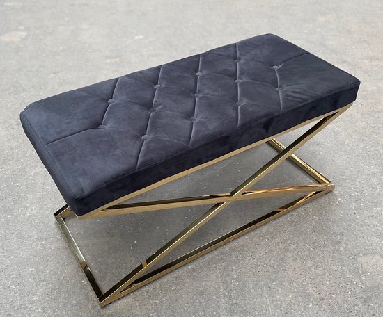 Zwart gestoffeerd hocker met gecapitonneerd zitvlak en een glanzend gouden X-vormig onderstel.