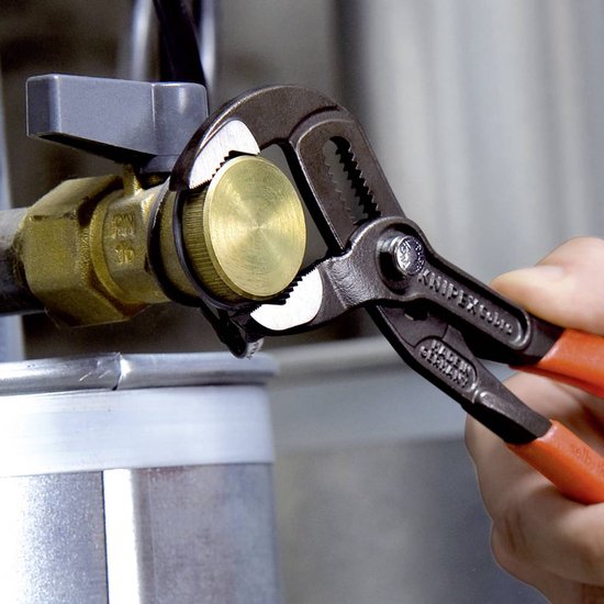 Knipex waterpomptang met oranje handvatten die een messing kraanaansluiting vastgrijpt.