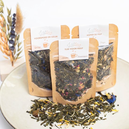 Drie Lottea theeverpakkingen: 'Voorspoed en Geluk', 'Tijd voor Feest' (aardbei/sinaasappel) en 'Hieper de Piep' (perzik). Losse thee met bloemen en fruit.