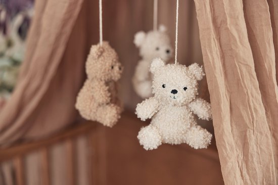 Drie teddyberen mobiel, zacht en knuffelbaar, hangend onder een roze hemeltje.