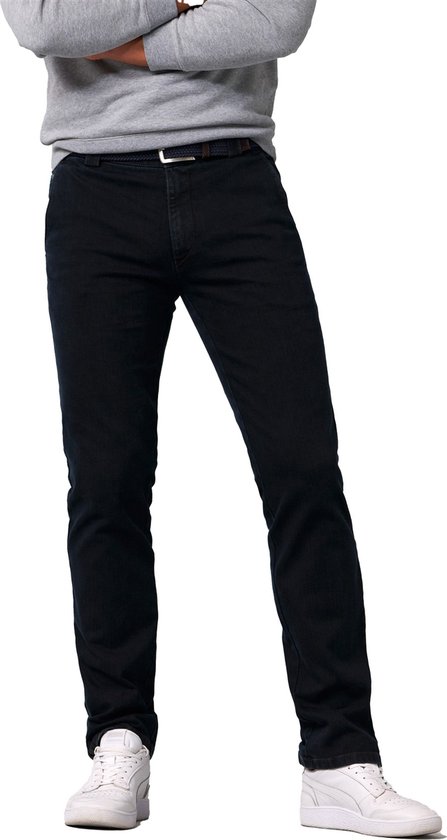 Man met een grijze sweater, donkerblauwe jeans, bruine riem en witte sneakers.