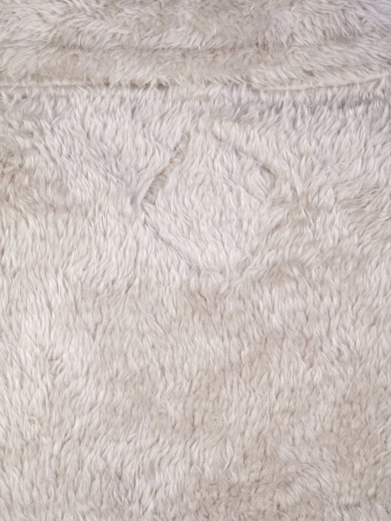 Close-up van de beige, zachte fleece stof van een bodywarmer.