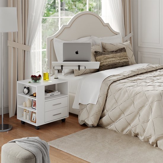 Table de chevet blanche avec deux tiroirs et étagères ouvertes, utilisée près d'un lit avec un ordinateur portable sur un plateau réglable.