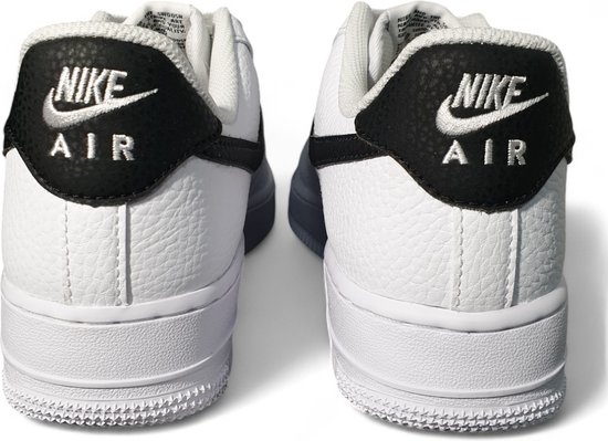 Achterkant van witte Nike Air Force 1 sneakers met zwarte 'NIKE AIR' logo's op de hiel.
