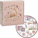 Roze knutseldoos met afbeelding van een hertje en bloemen. Naast de doos de inhoud: stickers, mozaïek, kleurpotloden, waterverf.